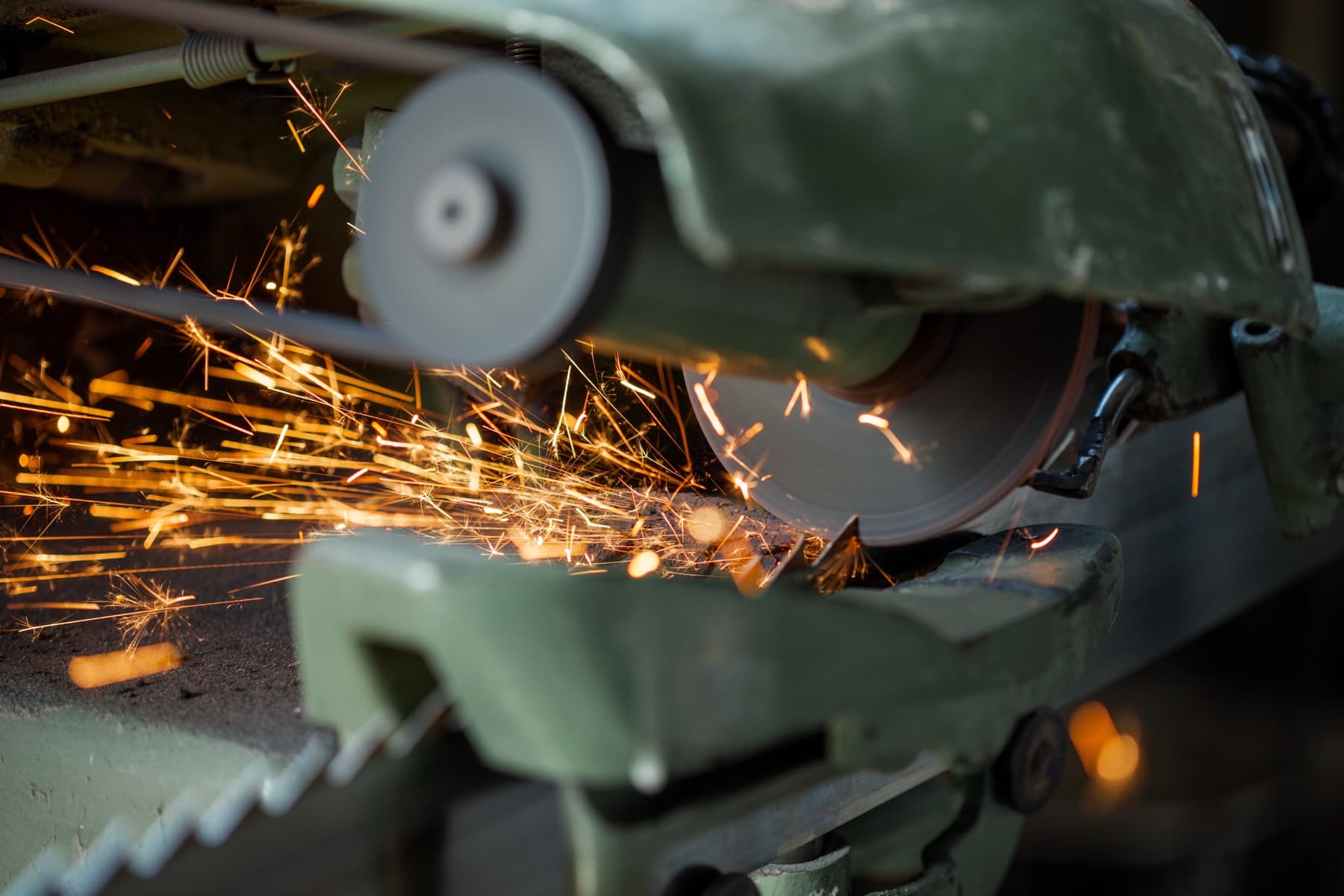 Circular industrial blade being sharpened on a workshop machine with sparks
